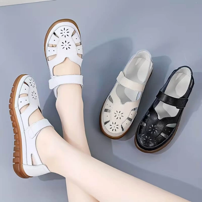 Comfortable white leather flat sandals featuring floral cutout details, shown next to a matching black pair on a grey surface.