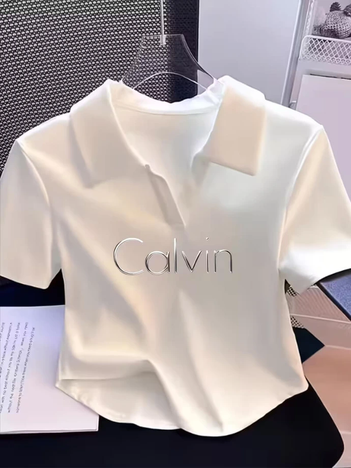 A crisp white collared t-shirt dress with "Calvin" branding on the front, displayed on a hanger.